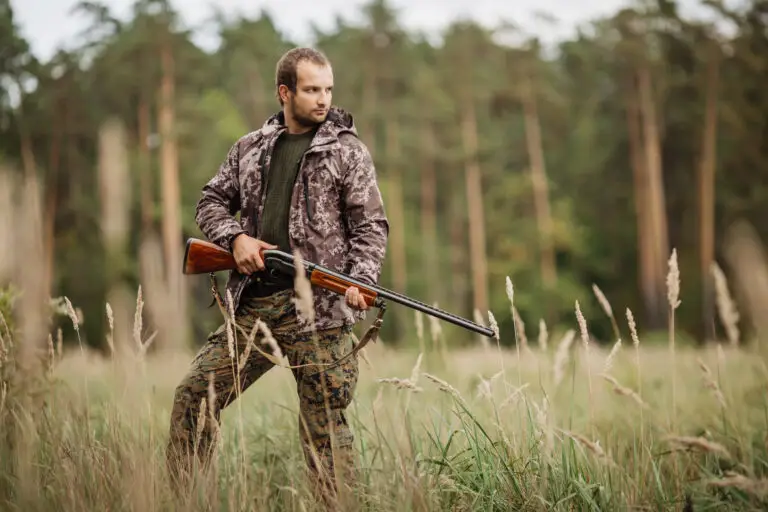 Jeune chasseur en tenue de camouflage, tenant un fusil de chasse, prêt pour une journée en pleine nature